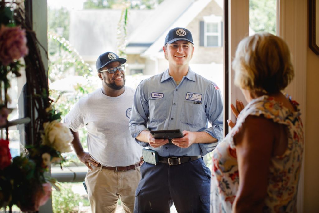 Meetze Plumbing technicians smiling greeting homeowner at front door