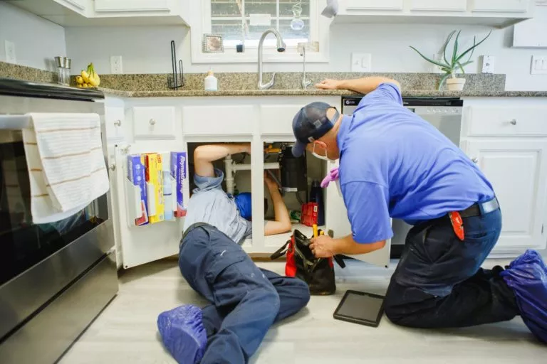 Meetze technician under kitchen sink repairing garbage disposal
