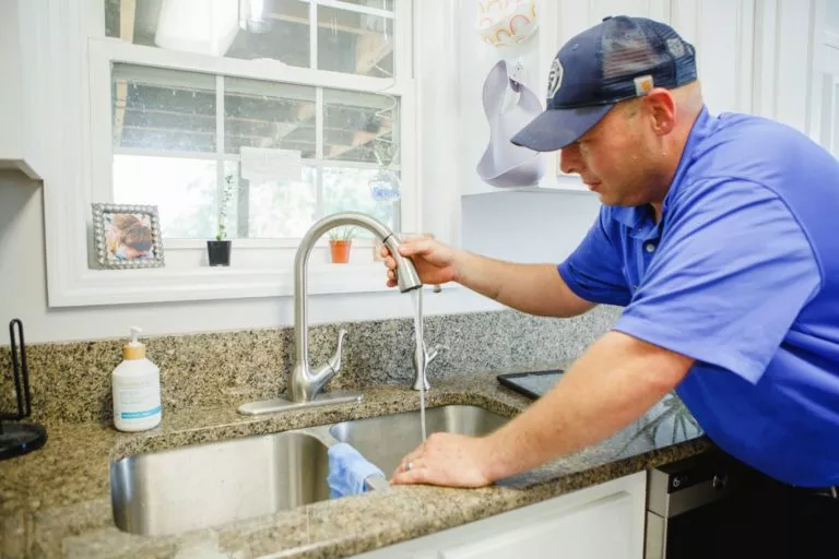 Meetze Plumbing technician adjusting kitchen sink faucet