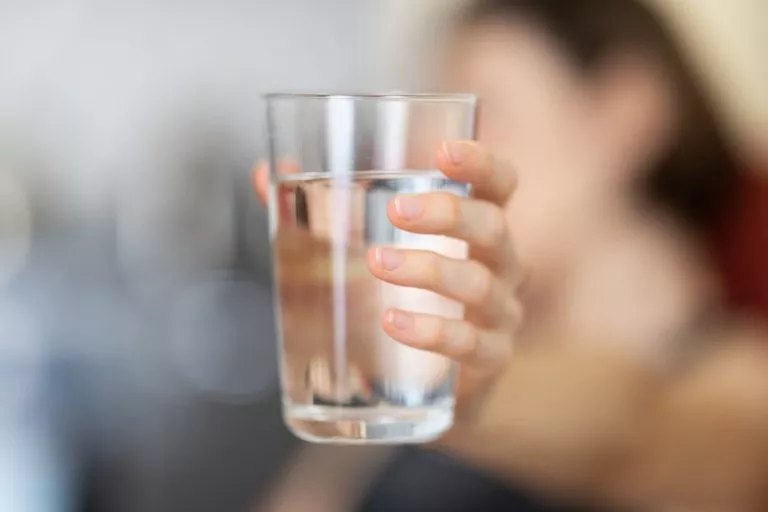 blurred woman with glass of water in hand