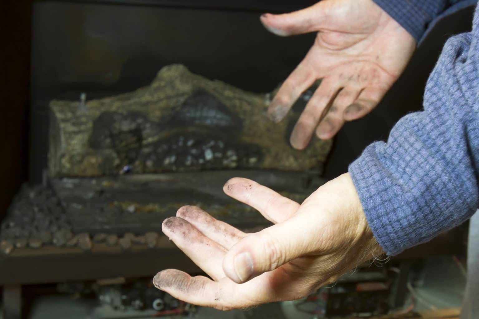 Dirty man hands in front of gas fireplace