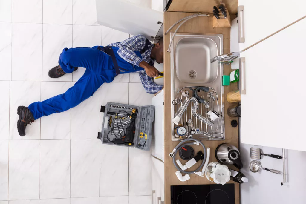 A plumber lying on the floor repairing the sink