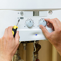 a plumbing technicians hands working on a water heater