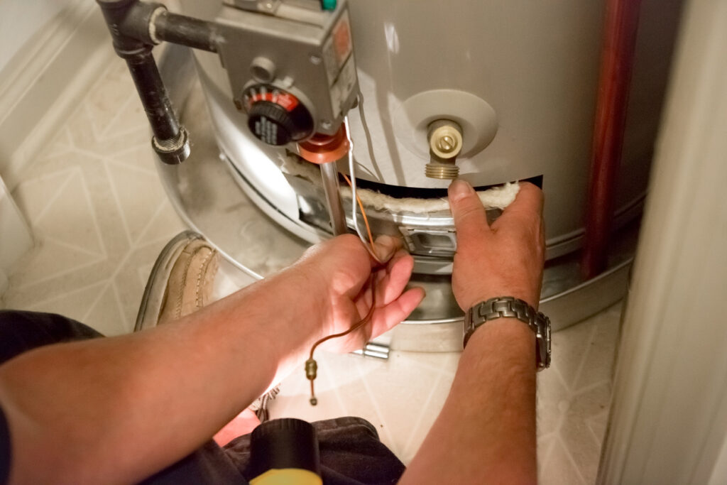 A plumber uses a flashlight to see the water heater and its panel